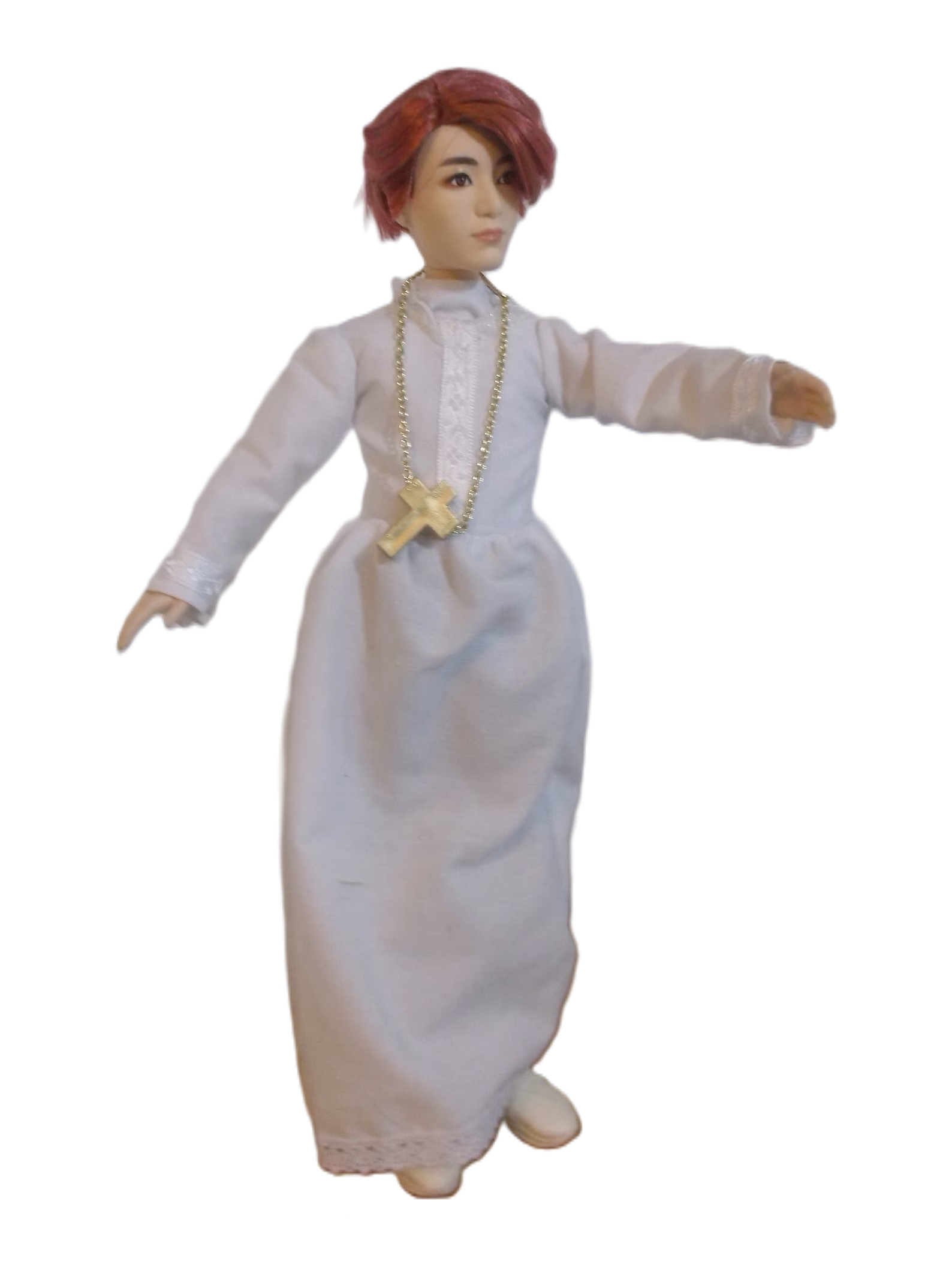 A photograph of a doll of Jeon Jungkook wearing the traditional vestments of a Catholic alter boy.